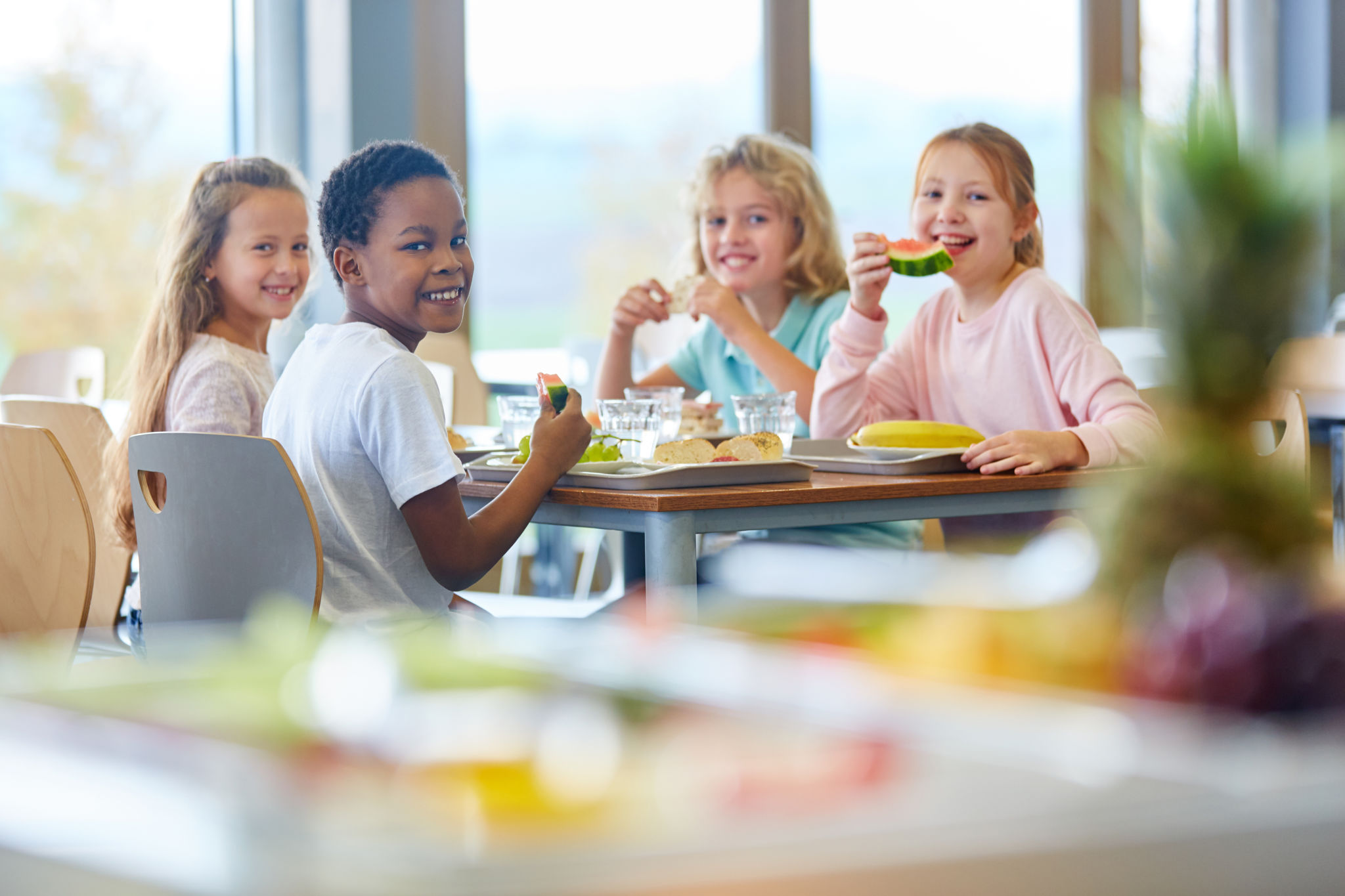 Gruppe Kinder als Freunde beim Mittagessen in der Cafeteria der Schule